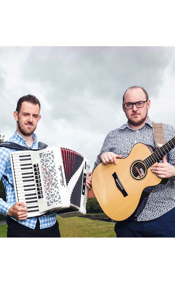 Image of two men, one holding a guitar and the other holding an accordion.